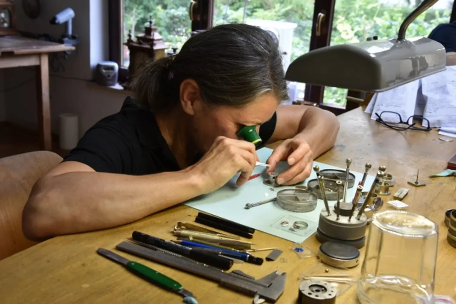 Petra Schmittbiel repariert mit der Lupe eine Uhr